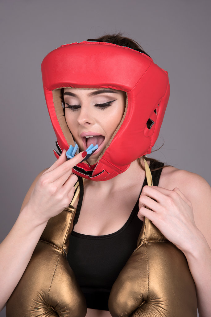 Attractive young boxer wearing a red leather head protector and hold a gum guard