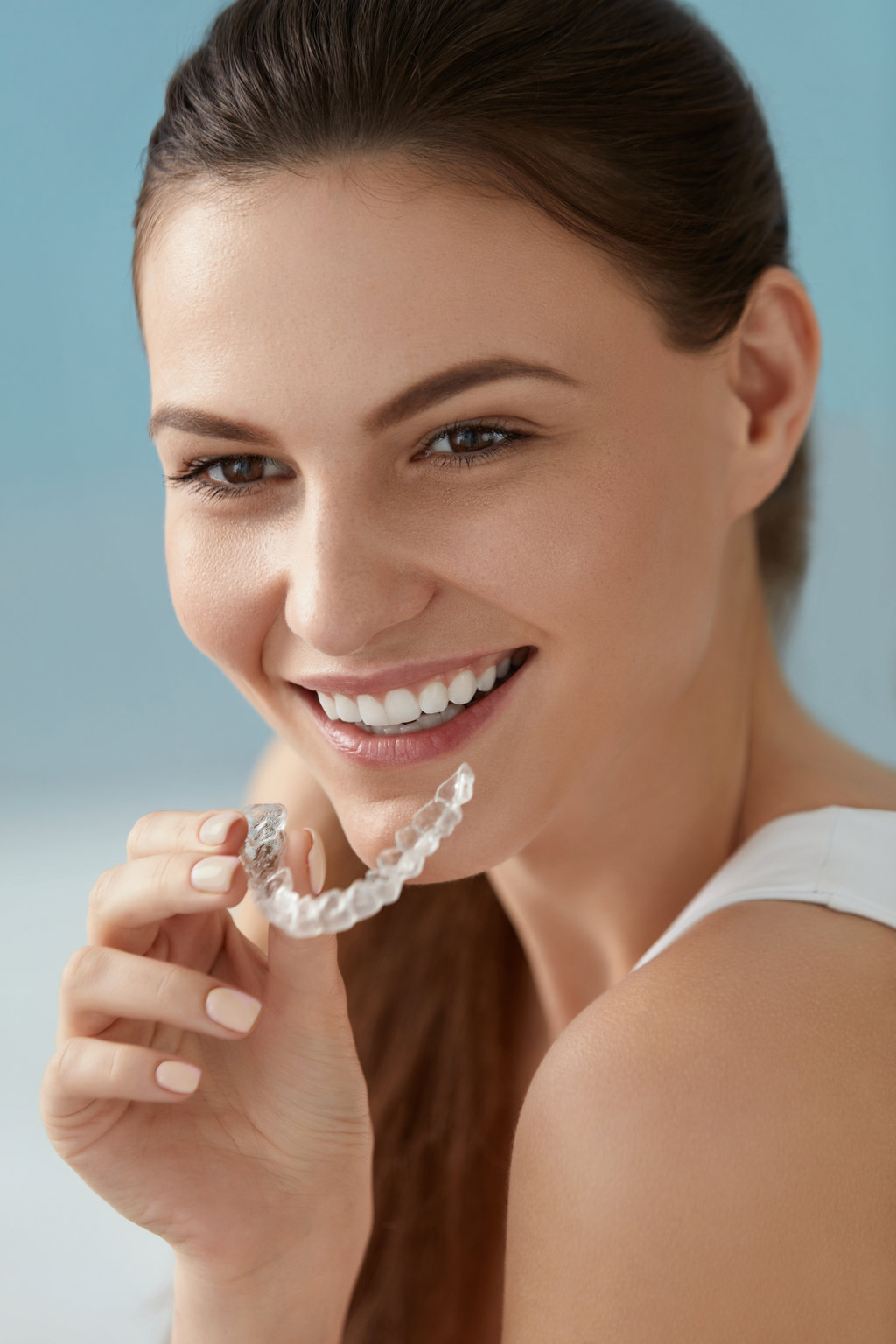 Dental care. Smiling woman with healthy teeth using removable clear braces aligner, orthodontic silicone trainer. Portrait girl with white smile using invisible whitening tray