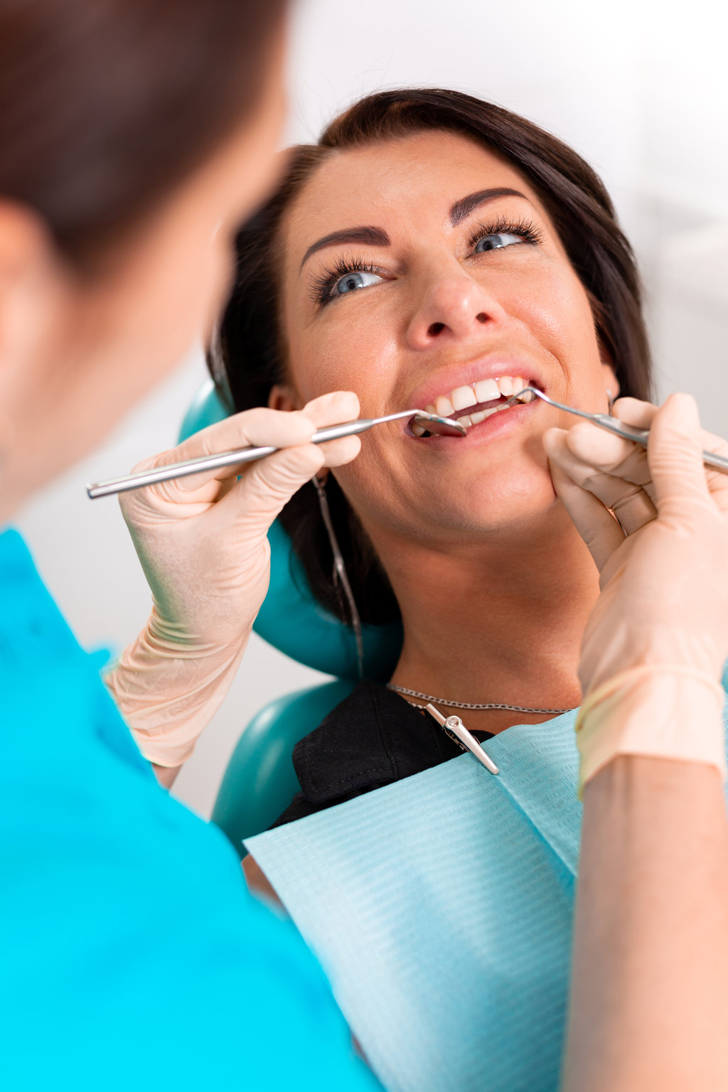 Putting dental braces to the woman's teeth at the dental office. Dentist examine female patient with braces in dental office. Close-up of a young attractive girl with braces on the teeth.