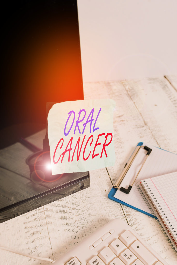 Conceptual hand writing showing Oral Cancer. Concept meaning the cancer of the lining of the lips mouth or upper throat Note paper taped to black screen near keyboard stationary